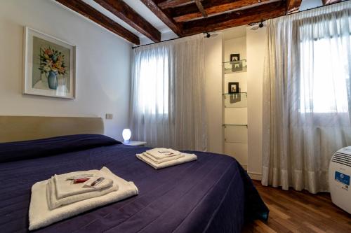 um quarto com uma cama roxa com toalhas em Veneziacentopercento Gorne Apartment em Veneza