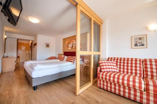 um quarto com uma cama, um sofá e um espelho em Astor Suites B&B em Selva di Val Gardena