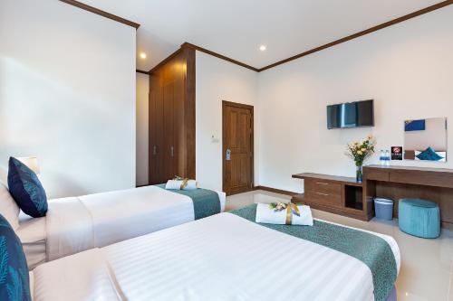 a hotel room with two beds and a tv at Lady Naya Villas - SHA Extra Plus in Rawai Beach