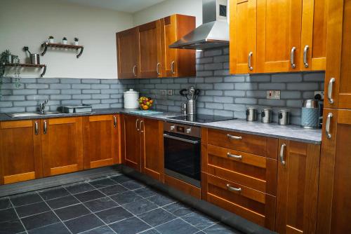 a kitchen with wooden cabinets and a stove top oven at Copper Oven apartments in Arbroath