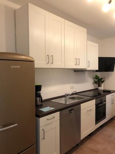 a kitchen with white cabinets and a stainless steel refrigerator at Pension Chen in Griesstätt