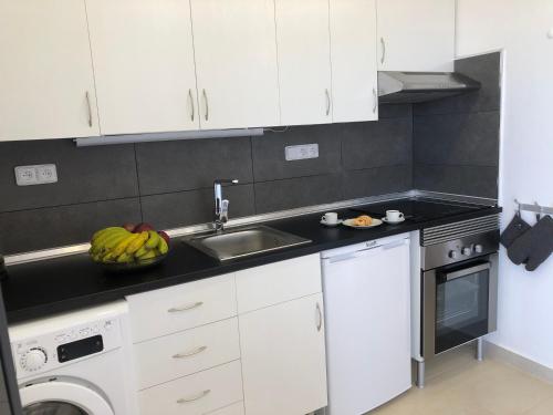 a kitchen with white cabinets and a sink and a dishwasher at Villa SCIROCCO Madeira - Ocean View in Machico