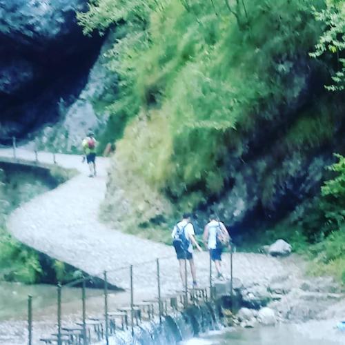 two people walking on a bridge over a river at casa vacanze al paesello in Orezzo