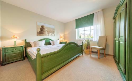 a bedroom with a green bed with a chair and a window at NTBM36001-Binnenseeblick in Neue Tiefe Fehmarn
