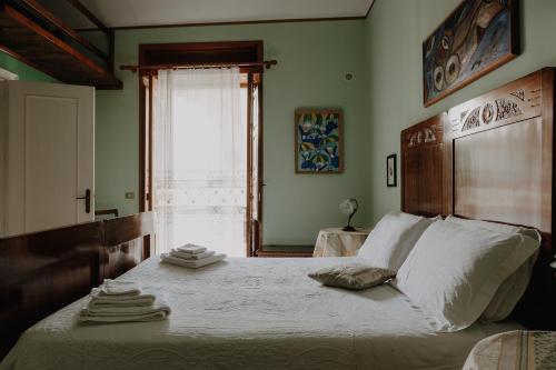 una camera da letto con un letto con lenzuola bianche e una finestra di La Baronessa B&B a Riposto