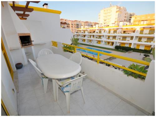une table et des chaises blanches sur le balcon d'un bâtiment dans l'établissement Apartamentos Capitolina, à Quarteira