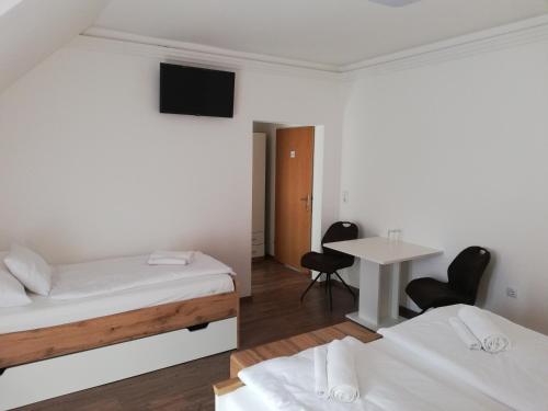 a room with two beds and a table with chairs at Levanda Panzió in Kópháza