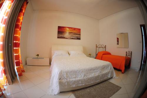 een slaapkamer met een wit bed en een oranje stoel bij The Last Floor in Torre del Greco