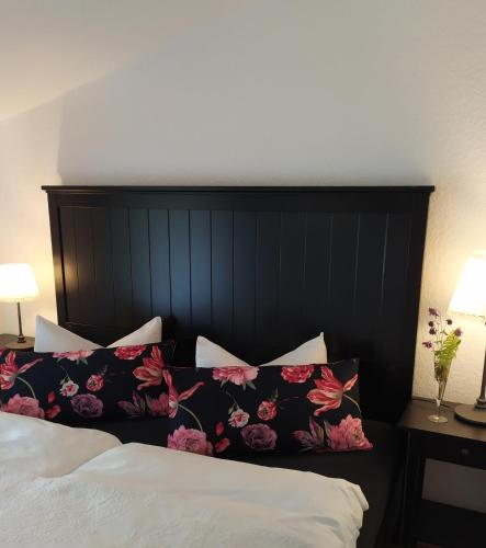 a bed with a black headboard with flowers on it at SchlossparkFerienwohnungen Rheinsberg mit Garten in Rheinsberg