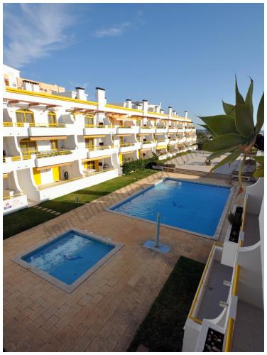 a large white apartment building with two swimming pools at Apartamentos Capitolina in Quarteira