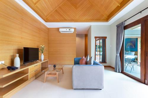 a living room with a blue couch and a tv at Lady Naya Villas - SHA Extra Plus in Rawai Beach