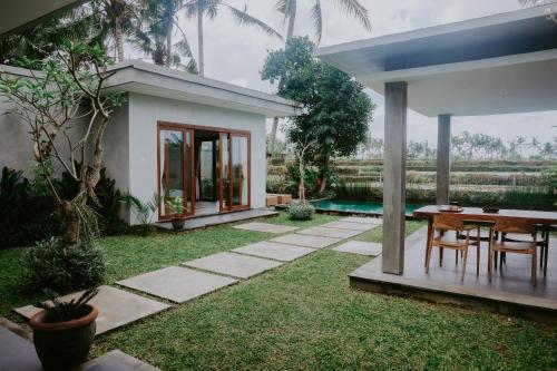 a garden with a table and chairs and a house at Anggira Villa Ubud in Ubud