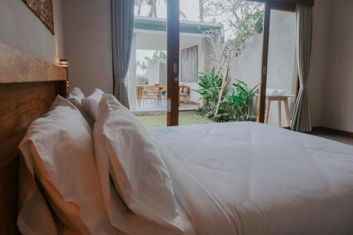 a bed with white sheets and pillows in a bedroom at Anggira Villa Ubud in Ubud