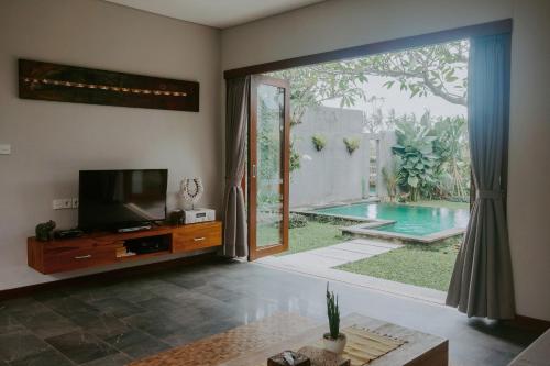 a living room with a television and a pool at Anggira Villa Ubud in Ubud