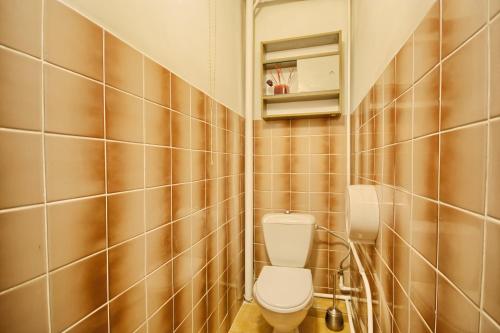 a bathroom with a toilet and a tiled wall at Poilsis Pas Tada in Druskininkai