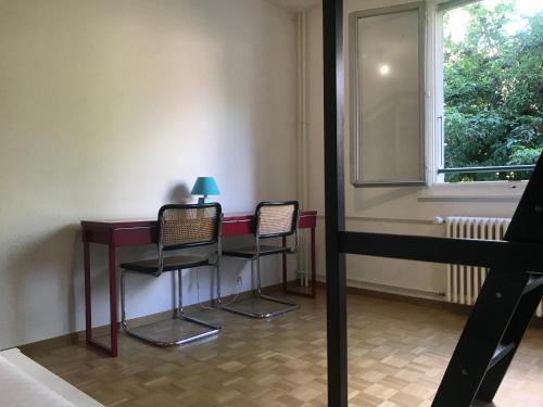 une chambre avec deux chaises, une table et une fenêtre dans l'établissement Geneva Bernex - shared appartement roomate homestay - tramway 14 TPG - ViaRhôna, à Genève