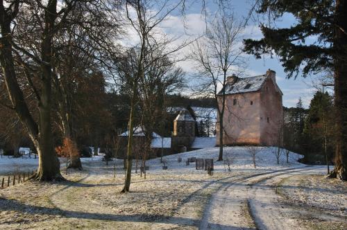 an old building in the snow with a bridge in the background at Barns Tower in Peebles