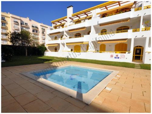 a swimming pool in front of a building at Apartamentos Capitolina in Quarteira