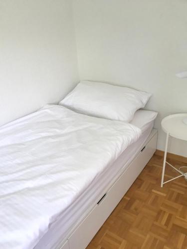 a bed with white sheets and a table in a room at Charmantes Apartment in Bern