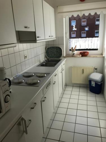 eine Küche mit weißen Schränken und einem Herd mit Backofen in der Unterkunft Ferienwohnung "Sielblick" in Dornumersiel in Dornum