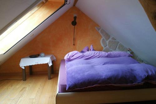a bedroom with a purple bed and a table at Ferienwohnung Roswitha in Blieskastel in Biesingen