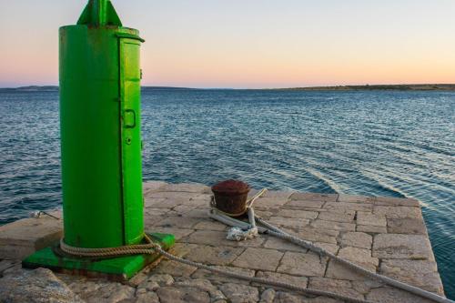 a green pole with a rope next to the water at Apartment Rino, only 30m from the sea in Pag