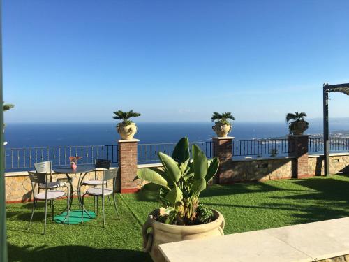 un patio con mesa, sillas y el océano en Casa Bucalo, en Taormina