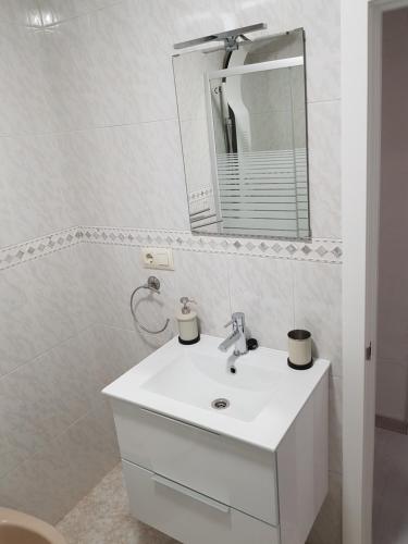 uma casa de banho branca com um lavatório e um espelho em El RiNCoNCiTo De Su em Gijón
