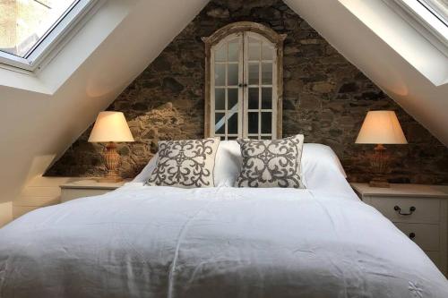 a bedroom with a large white bed with two lamps at Barns Bothy in Peebles