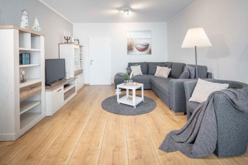 a living room with a gray couch and a tv at Strandkorb in Fehmarn