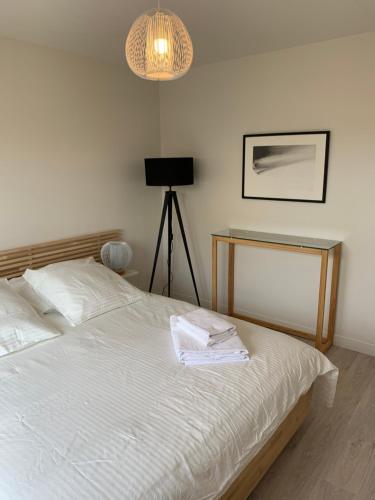 a bedroom with a bed with white sheets and a lamp at La Maison de Juliette in Agon Coutainville