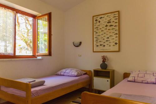 a bedroom with two beds and a window at Apartment Rino, only 30m to the sea in Pag