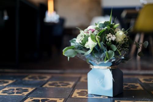a blue vase with a bouquet of flowers on a table at Hotel Restaurant La Musardiere in Giverny
