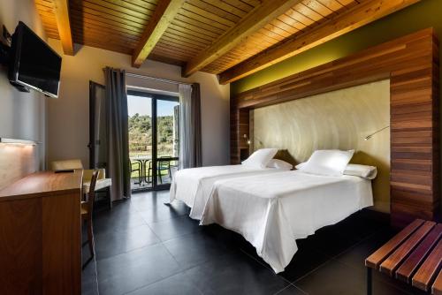 two beds in a hotel room with a balcony at Hotel Spa Aguas de los Mallos in Murillo de Gállego