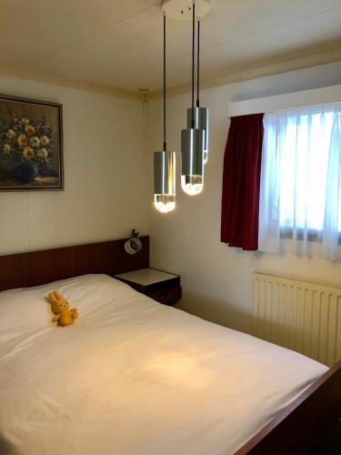 a teddy bear sitting on a bed in a bedroom at Retro Relax Resort midden in het bos op de Veluwe in Putten in Putten