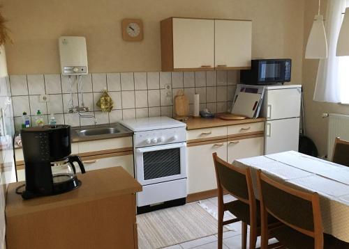 ZurowにあるFerienwohnung Storchenblickのキッチン(白い家電製品、テーブル、椅子付)
