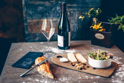 a table with a bottle of wine and a plate of food and a glass at Hotel Restaurant La Musardiere in Giverny