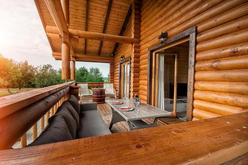 a porch of a log cabin with a table on it at Country Lodge Vuković in Rakovica