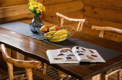 a wooden table with a book and a bowl of fruit at Country Lodge Vuković in Rakovica