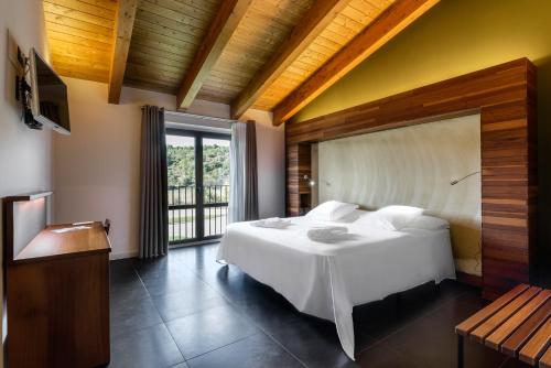a bedroom with a large white bed and a window at Hotel Spa Aguas de los Mallos in Murillo de Gállego