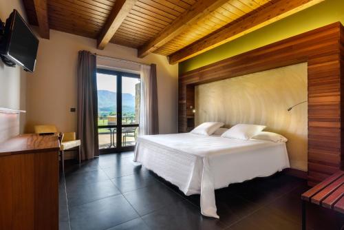 a bedroom with a white bed and a balcony at Hotel Spa Aguas de los Mallos in Murillo de Gállego