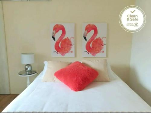 a bed with a red pillow and two paintings of flamingos at BLISS WHITE HOUSE in Sintra
