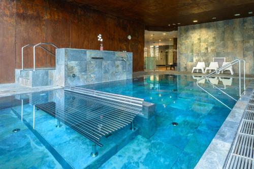 a large pool with blue water in a building at Hotel Spa Aguas de los Mallos in Murillo de Gállego