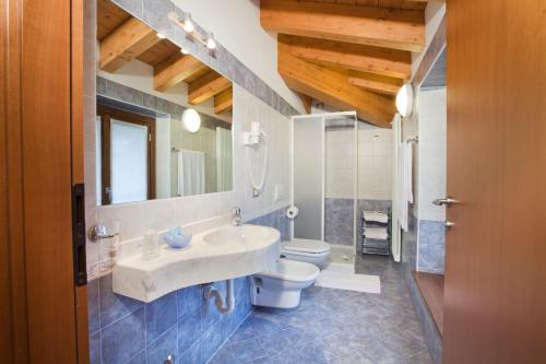 bagno con lavandino, servizi igienici e specchio di Hotel Ferrari a Castione della Presolana