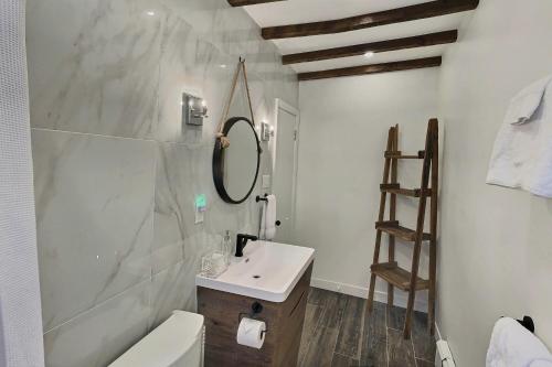 ein weißes Badezimmer mit einem Waschbecken und einem Spiegel in der Unterkunft Gite du Survenant Montreal in Montreal
