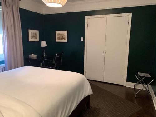 a bedroom with a white bed and a green wall at Gite du Survenant Montreal in Montréal