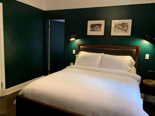 a bedroom with a large white bed with green walls at Gite du Survenant Montreal in Montréal