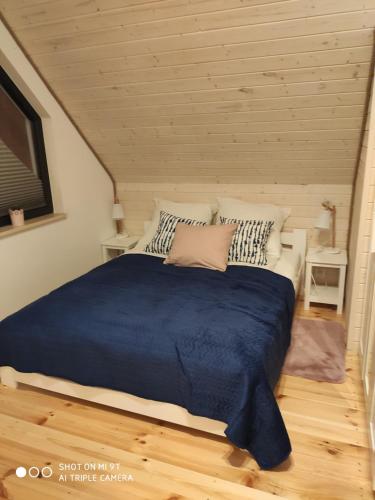ein Schlafzimmer mit einem großen Bett mit einer blauen Decke in der Unterkunft Domki letniskowe Marcinowa Wola in Miłki
