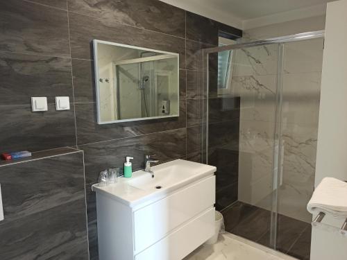 Un baño con lavabo blanco y ducha. en Villa Novak, en Rab