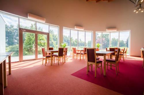 a dining room with tables and chairs and windows at HOTEL A4 Airport Kraków MOP Morawica in Aleksandrowice